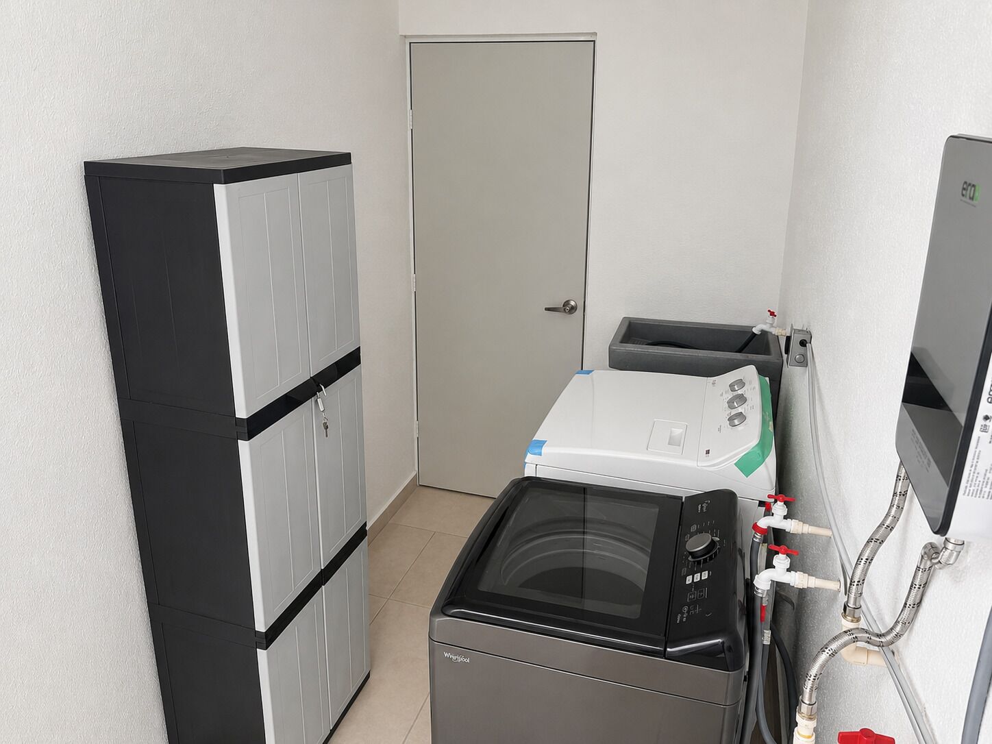 Ein kleiner Hauswirtschaftsraum mit Waschmaschine, Trockner und Stauraumschränken.