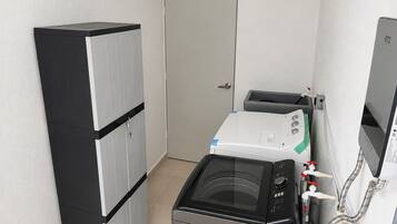 Een kleine wasruimte met een wasmachine, droger en opslagkasten.