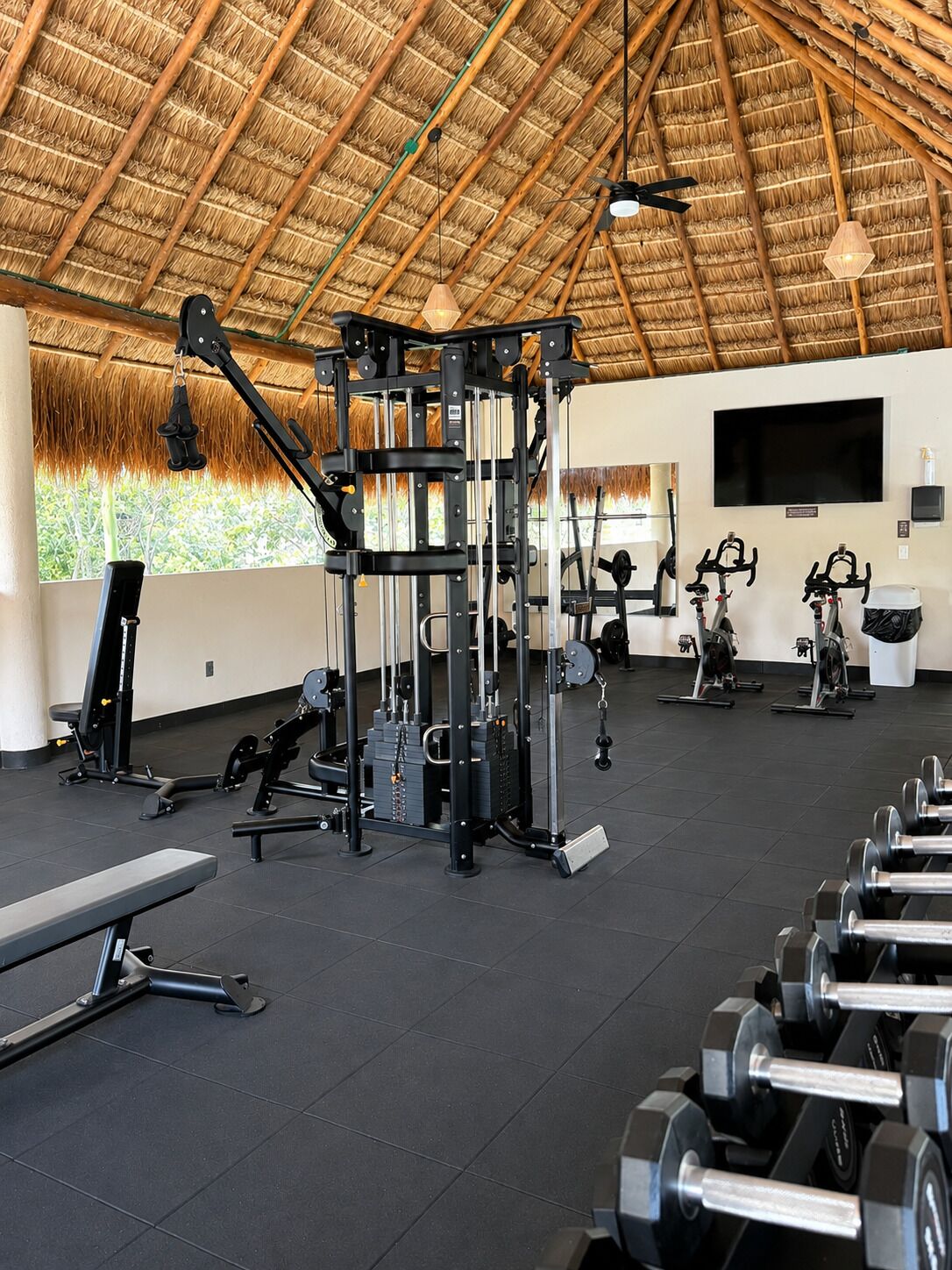 Une salle de sport équipée de divers appareils d’exercice, d’un banc et d’haltères.