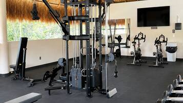 Une salle de sport équipée de divers appareils d’exercice, d’un banc et d’haltères.