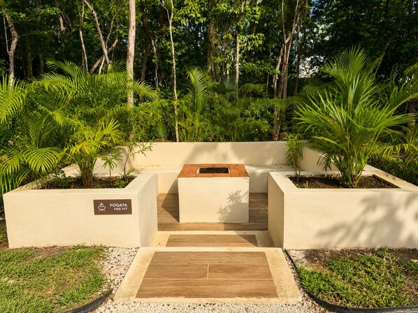A fire pit area surrounded by lush greenery and trees.