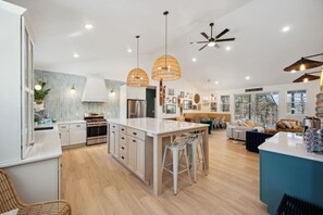 A modern kitchen with a central island, bar stools, and pendant lighting.