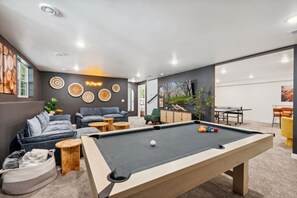 A modern living room with a pool table, comfortable seating, and decorative wall art. - Modern Sister Bay Retreat | Prime Location (Sister Bay)