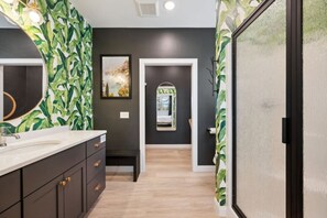 A modern bathroom with a dark wall, a white sink, and a mirror.