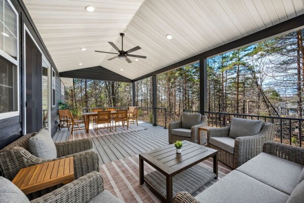 A covered outdoor area with a ceiling fan, a dining table with chairs, and wicker furniture.