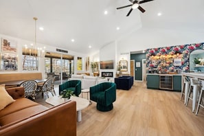 A spacious living area with a sofa, chairs, a coffee table, and a kitchen area with a bar.
