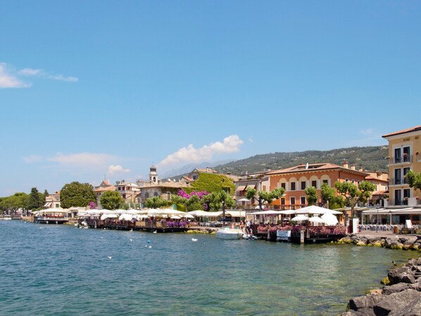 A waterfront hotel with outdoor seating, a bell tower, and a view of the water.