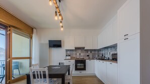 Een moderne keuken met witte kasten, een houten eettafel en stoelen.