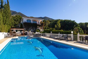 A swimming pool with dolphin designs, outdoor seating, and a mountain backdrop. - Casa Bella | pool - sea views - garden (Mijas)
