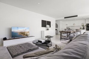 A modern living room with a flat-screen TV, a round coffee table, and a sofa.