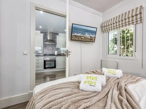 Ein Schlafzimmer mit einem Bett, einem Fernseher und einem Fenster mit Blick auf Grünflächen.