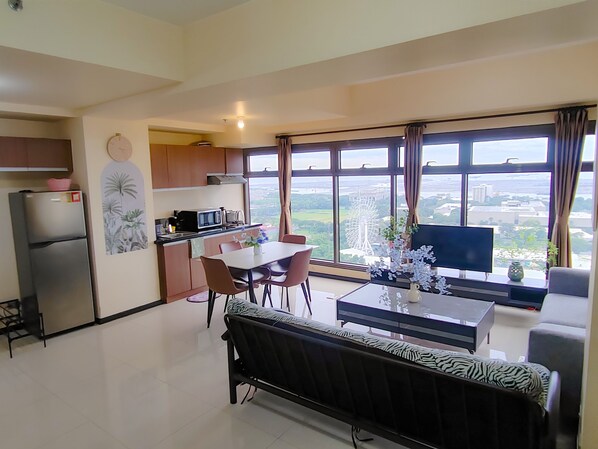 Ein modernes Wohnzimmer mit Essbereich, Küche und großen Fenstern mit Blick auf die Stadt.
