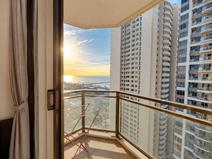 Un balcón con vista a edificios altos y un atardecer.