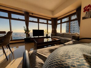 Una habitación de hotel moderna con una cama grande, un sofá, un televisor y un escritorio.