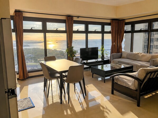 A modern living room with a large window, a sofa, a coffee table, and a TV.