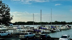 A marina with boats docked, a white pickup truck, and a white car parked by the water. - Your Lake Erie Islands' Getaway Condo for 6 with a Clubhouse and Pool! (Port Clinton)