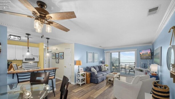 A spacious living area with a dining table, a sofa, and a balcony with a view. - Your Lake Erie Islands' Getaway Condo for 6 with a Clubhouse and Pool! (Port Clinton)