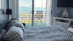 A bedroom with a bed, a chair, a TV, and a view of the beach. - Your Lake Erie Islands' Getaway Condo for 6 with a Clubhouse and Pool! (Port Clinton)