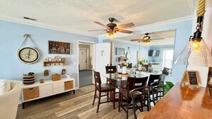 A dining area with a wooden table and chairs, a ceiling fan, and a wall-mounted clock. - Your Lake Erie Islands' Getaway Condo for 6 with a Clubhouse and Pool! (Port Clinton)