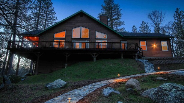 A wooden cabin with a balcony, large windows, and a stone pathway leading to the entrance. - Red Tail Retreat in Mariposa (Mariposa)