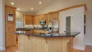 A kitchen with wooden cabinets, stainless steel appliances, and a granite countertop island. - Red Tail Retreat in Mariposa (Mariposa)