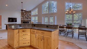 A spacious kitchen with a large island, wooden cabinets, and a stone accent wall. - Red Tail Retreat in Mariposa (Mariposa)