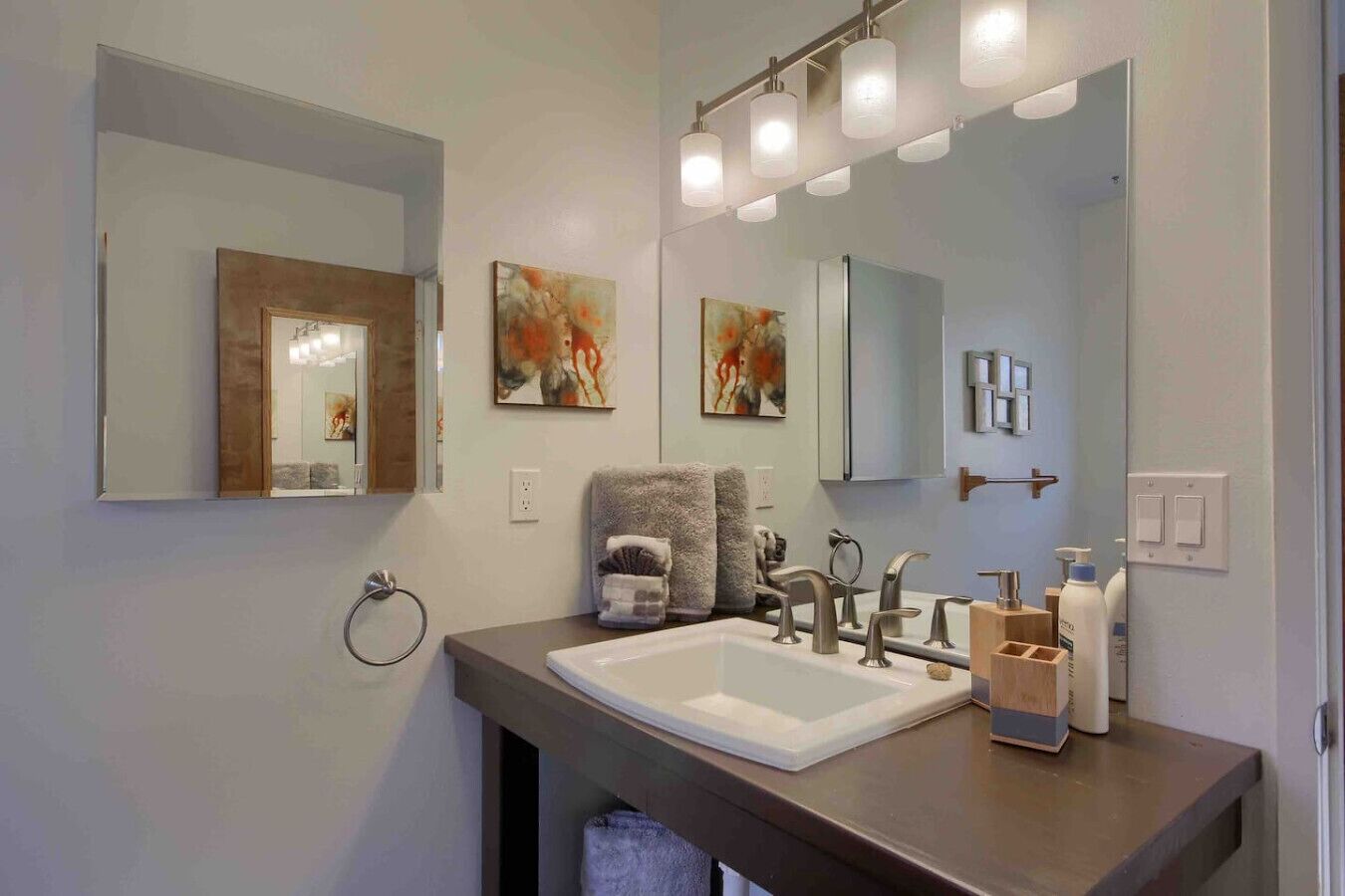 A modern bathroom with a large mirror, two sinks, and a towel rack.
