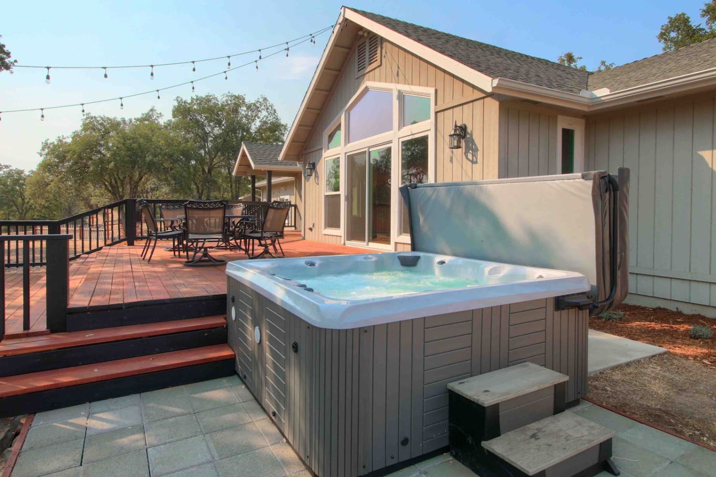 A hot tub in a backyard with a covered patio and outdoor furniture.