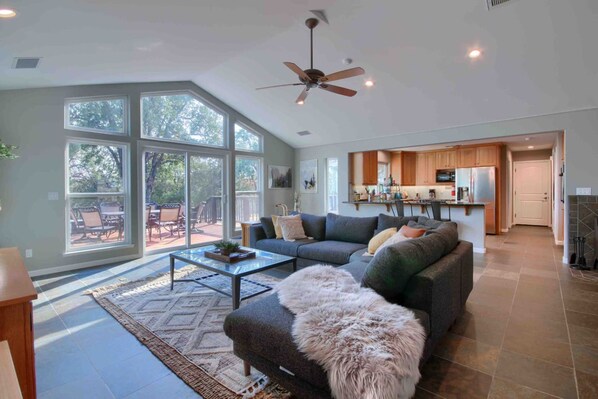 A spacious living room with a large window, a ceiling fan, and a view of the outdoors.