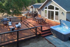 A deck with outdoor furniture, a hot tub, and a covered patio area.