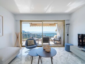 A modern living room with a sofa, two armchairs, a coffee table, and a TV on a stand. - 2-Br Apartment Sea View & Pool – Cannes Croix des Gardes (Cannes)