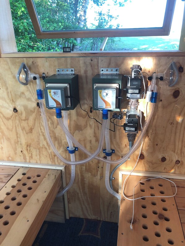 A wooden room with two control panels, a window, and a wooden bench.