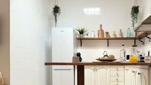 A kitchen with white cabinets, a white refrigerator, wooden stools, and a wooden countertop with various items. - Canaryislandshost l Olympica 5 (Tahiche)