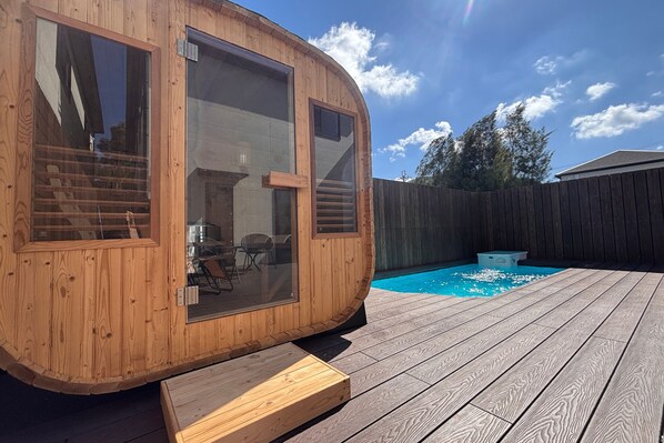Una cabaña de madera con ventanas amplias, una terraza y una piscina.