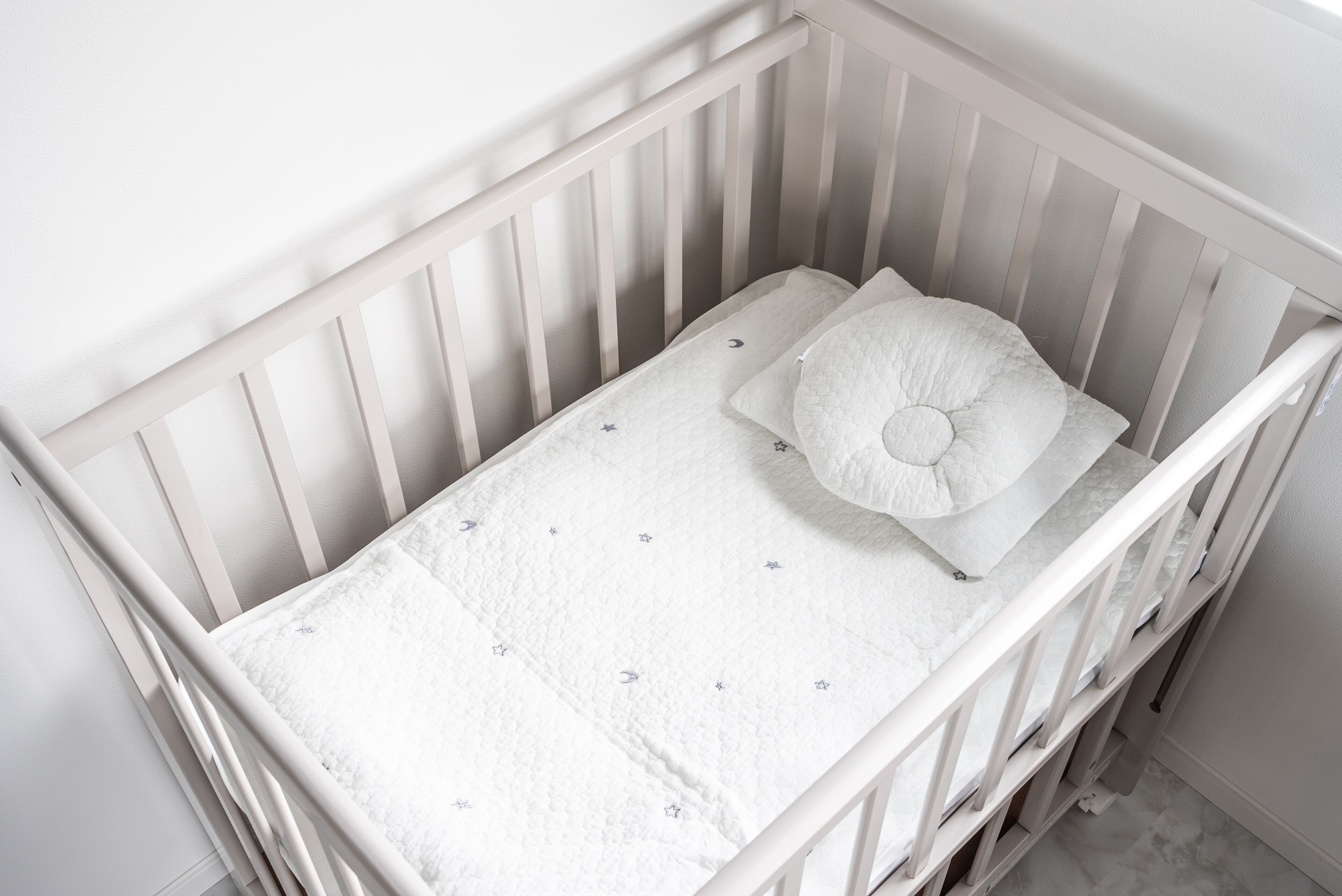 Un berceau blanc avec un matelas matelassé et un oreiller.
