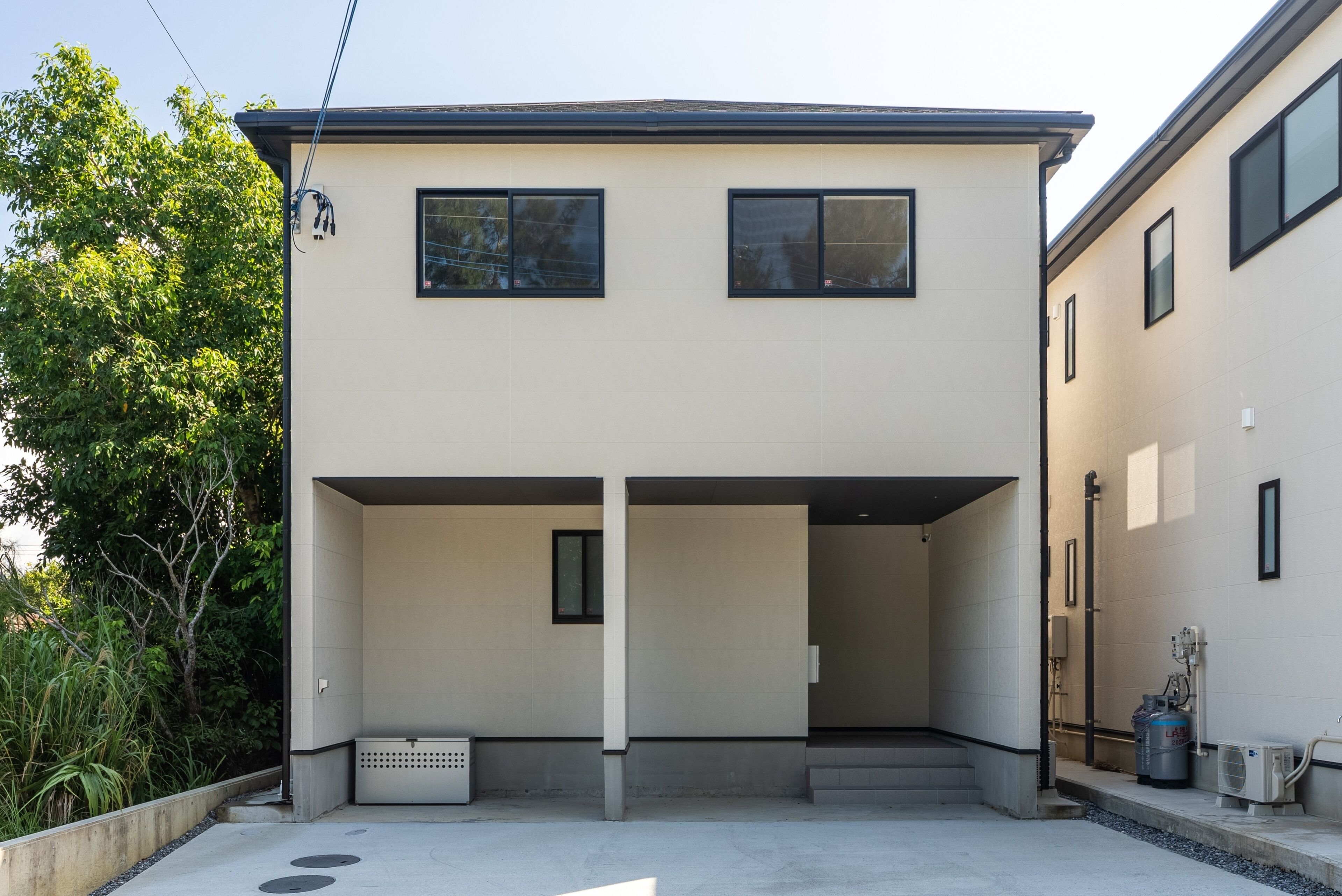 A modern two-story building with a flat roof and a covered entrance area.