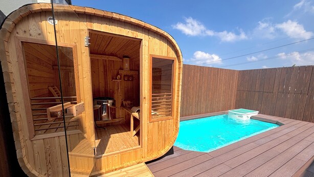 A wooden hot tub cabin with a built-in seating area and a small pool.