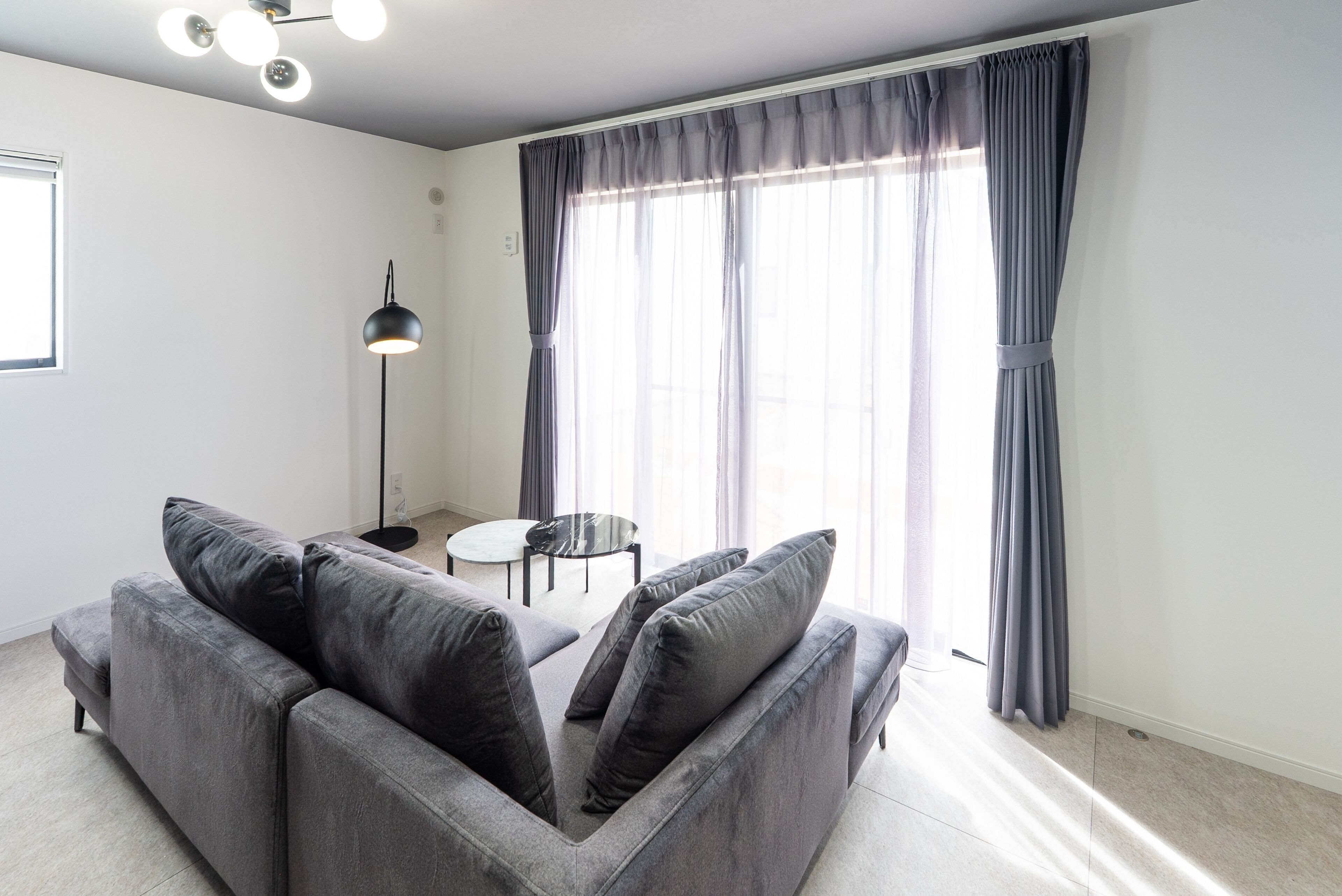 A modern living room with a grey sofa, a small round table, and a floor lamp.