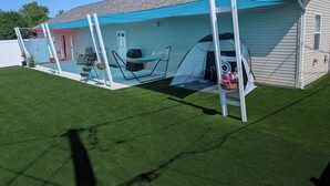 Une maison dotée d’un patio couvert comprenant un hamac, un barbecue et une balançoire.