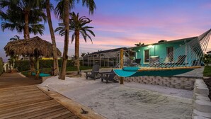 Un resort frente a la playa con una hamaca, mobiliario exterior y una terraza de madera.