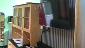 Une pièce avec un meuble en bois, un téléviseur fixé au mur, qui est décoré de rayures, et un petit bureau avec un clavier.