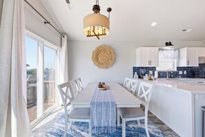 A modern kitchen with white cabinetry, a central island, and a dining area with a white table and chairs.
