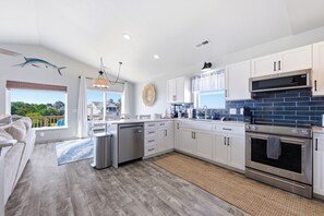 A modern kitchen with white cabinets, a stainless steel oven, and a view of the outdoors.