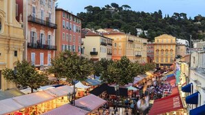 A bustling street market with colorful buildings and trees lining the street.