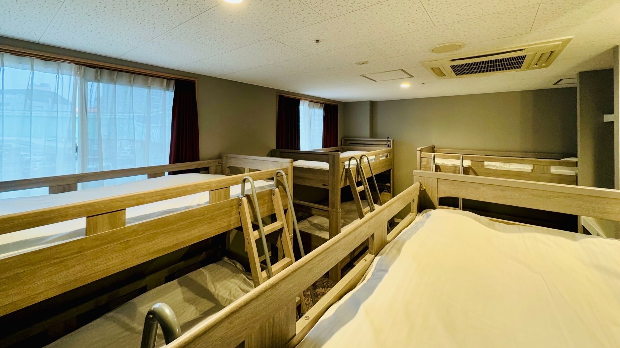 Une chambre d’hôtel avec des lits superposés, un bureau et une fenêtre avec des rideaux.