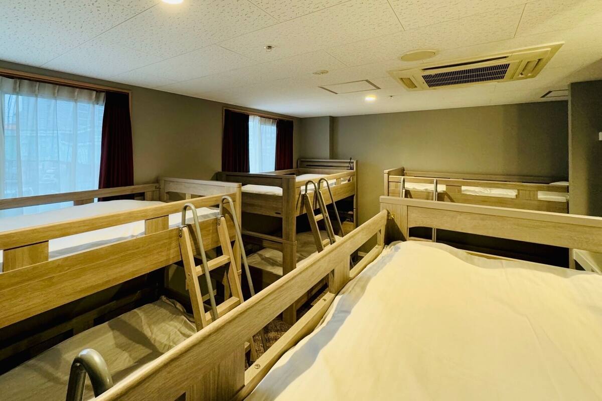 A hotel room with bunk beds, a desk, and a window with curtains.