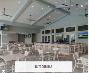 A spacious indoor area with multiple tables and chairs, ceiling fans, and large windows.