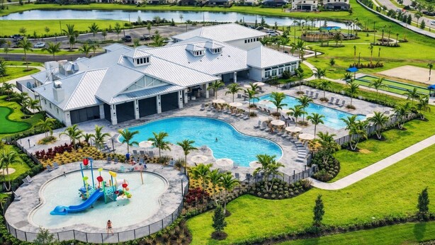 Un resort con una amplia piscina, un tobogán acuático y un campo de golf al fondo.