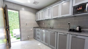 Una cocina moderna con armarios grises, un lavamanos de acero inoxidable y un horno empotrado.