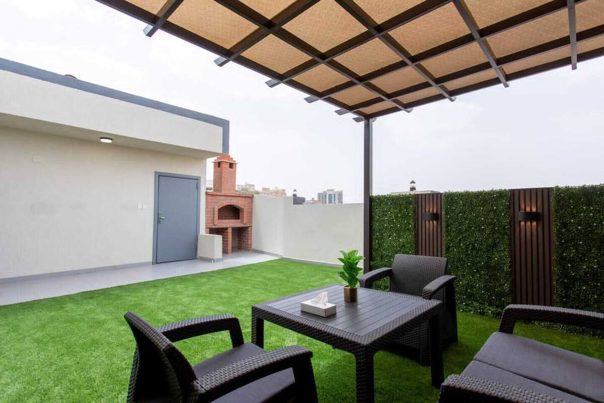 Un terrat amb terrassa, un forn de rajola, mobles d'exterior i un jardí verd.